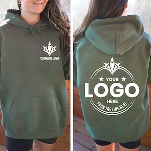 May include: An olive green hooded sweatshirt featuring a white graphic on the front chest that reads COMPANY LOGO. The back displays a large white circular emblem with a central design, two stars, and the text YOUR LOGO HERE YOUR TAGLINE HERE.