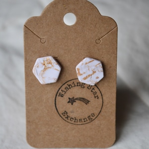 Könnte beinhalten: Ein Paar weiße sechseckige Ohrstecker mit goldenen Flocken auf einer braunen Karte mit dem Text "Wishing Star Exchange".