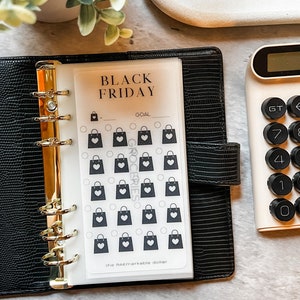 May include: A black and white sticker sheet with a shopping bag icon and a heart. The sticker sheet says "Black Friday" and "Goal" at the top and "the RAEMarkable dollar" at the bottom.