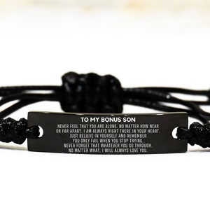 May include: Black braided bracelet with a rectangular black metal plate. The plate has the text "TO MY BONUS SON" and a loving message. The bracelet is adjustable and features a sliding knot closure.