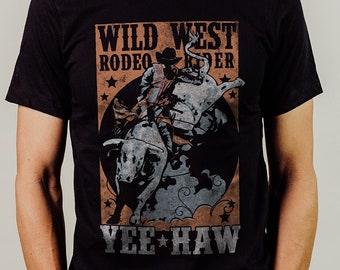 May include: A black t-shirt with a vintage-style graphic of a cowboy riding a bull. The graphic has the text "WILD WEST RODEO RIDER" and "YEE HAW" in a distressed font.