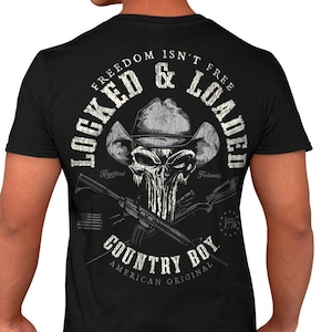 May include: Black t-shirt with a white graphic design featuring a skull wearing a cowboy hat and crossed rifles. The text "Freedom Isn't Free Locked & Loaded Country Boy American Original" is printed on the shirt.