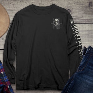 Op de afbeelding: Zwart langarm T-shirt met een witte schedel en gekruiste botten afbeelding op de linker borst en de tekst "LOCKED & LOADED" op de rechter mouw.