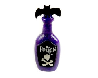 May include: A purple glass bottle with a black bat on top. The bottle has a white label that says "Poison" with a skull and crossbones.