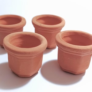 May include: Four small, terracotta-colored flower pots. Each pot has a rounded rim and a slightly tapered, octagonal body. The pots are unglazed and have a natural, earthy appearance, perfect for small plants or succulents.
