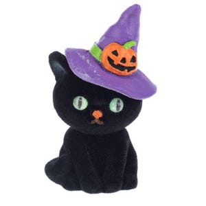 May include: A black plush cat wearing a purple witch hat with a jack-o-lantern on top. The cat is sitting with its paws tucked under its body.