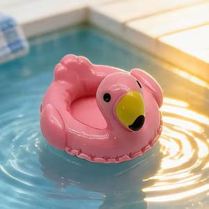May include: A small, pink, inflatable-style flamingo pool float toy with a yellow beak and black eyes. The flamingo has a circular, ring-shaped body with a molded head and neck extending from the front, designed to float on water surfaces.