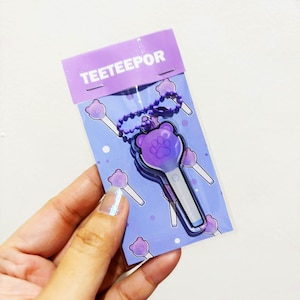 May include: A purple bear-shaped light stick keychain with a paw print design on the head, attached to a purple ball chain. The item is packaged in a clear plastic sleeve with a purple header card featuring the text TEETEEPOR and paw prints.
