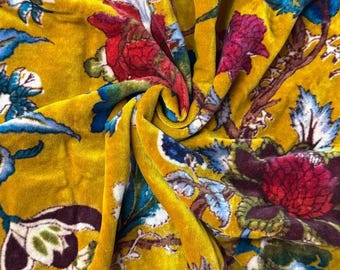 Puede incluir: Primer plano de una tela de terciopelo amarillo vibrante con un estampado floral. El diseño presenta grandes flores estilizadas en tonos rojos, azules y morados. La tela tiene una textura suave y lujosa y un ligero brillo.