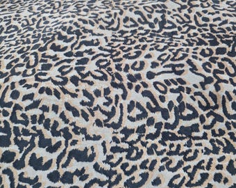 Tela de terciopelo con estampado de leopardo en beige y negro.