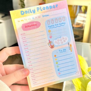 May include: A rainbow-colored daily planner with a schedule, goals for today, and to-do list. The planner has a cute bubble tea illustration and a mood tracker with smiley faces.