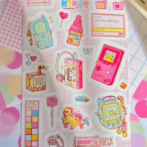 May include: A sheet of colorful stickers with a retro theme. Designs include a pink Game Boy with Pikachu, a cassette player, a baby bottle, a Tamagotchi, and a cell phone. The word "Kindy" is at the top.