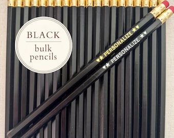 May include: A collection of black pencils with red erasers and gold-colored metal ferrules. Two pencils are placed diagonally across the others, each featuring the text "PERSONALIZE" with star and heart symbols. A circular label reads "BLACK bulk pencils".