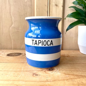 Può includere: Vaso in ceramica a righe blu e bianche con la scritta "TAPIOCA" stampata in nero sul davanti.