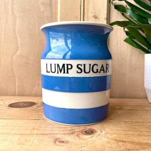 May include: A blue and white striped ceramic sugar jar with the words "LUMP SUGAR" printed on the front.