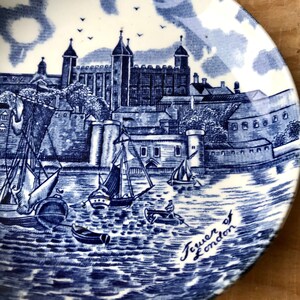 Peut inclure: Soucoupe en céramique bleue et blanche représentant la Tour de Londres et des bateaux sur la Tamise. La soucoupe porte l'inscription "Tower of London".