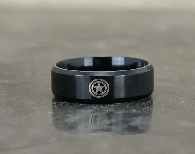 May include: A black ring with a silver star inside a circle design.