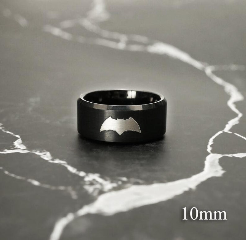 May include: A black ring with a silver Batman logo. The ring is 10mm wide.