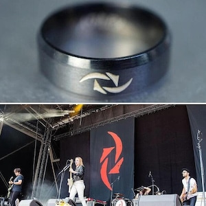 Peut inclure: Une bague en métal noir avec un symbole gravé en argent. Le symbole est un motif stylisé de deux croissants qui se chevauchent.