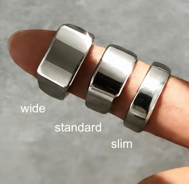May include: Three polished silver-tone metal rings of varying widths arranged on a finger. The rings are labeled with white text as wide, standard, and slim, indicating their respective band thicknesses and surface profiles.
