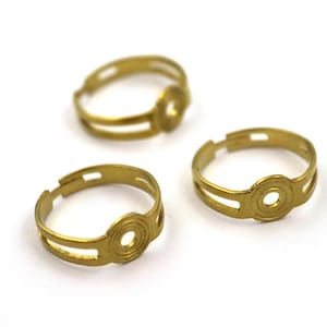 Op de afbeelding: Drie gouden metalen ringen met een ronde opening in het midden. De ringen zijn ontworpen om een ​​hanger of bedel te houden.