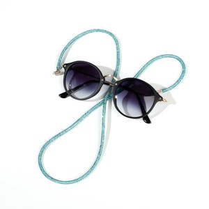 May include: Black round sunglasses with a blue glitter eyeglass chain.
