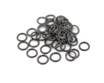 May include: A pile of black jump rings, a type of metal ring used in jewelry making.