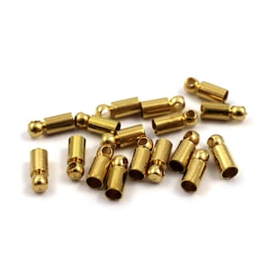 Puede incluir: Un grupo de tapones de metal de color dorado con una bola en un extremo. Estos tapones se utilizan para la fabricación de joyas y la artesanía.