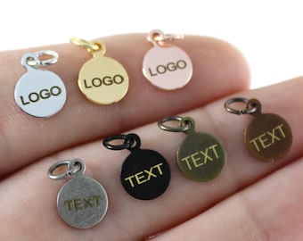 May include: Six round metal charms with jump rings. The charms are silver, gold, rose gold, black, antique silver, and brass. Each charm has the word "LOGO" or "TEXT" engraved on it.