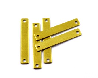 May include: Five gold-colored metal bar pendants with holes at each end. The bars are arranged in a stack, with the top bar slightly offset from the others.
