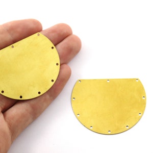 Può includere: Due forme in metallo a forma di semicerchio di colore dorato con fori attorno ai bordi. Le forme hanno un diametro di circa 7,5 cm.