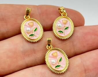 May include: Three gold-colored oval pendants with a pink enamel background. Each pendant features a flower design with a pearl and green leaves. The pendants have a textured border and a loop for a chain.