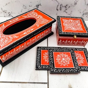 Pode incluir: Conjunto de quatro  copos de apoio vermelhos e pretos com desenhos de mandalas brancas, um porta-guardanapos vermelho e preto com um desenho de mandala branco e uma caixa vermelha e preta com um desenho de mandala branco.