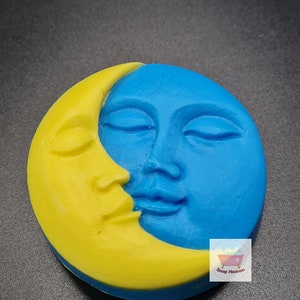 May include: A round soap bar with a celestial design. The soap features a yellow crescent moon and a blue face with closed eyes. The Soap Heaven logo is visible in the lower right corner.