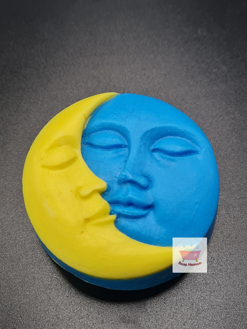 May include: A round soap bar with a celestial design. The soap features a yellow crescent moon and a blue face with closed eyes. The Soap Heaven logo is visible in the lower right corner.