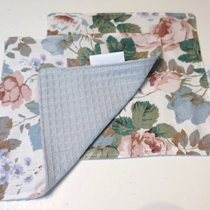 May include: Two gray and white floral kitchen dish towels with a waffle texture on the back side. The towels are folded in half and the brand name "Chrivals" is visible on the bottom right corner of the towel.