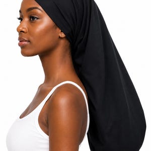 May include: A solid black long hair bonnet made of soft fabric. The bonnet features a fitted band around the forehead and a long, tubular section that extends down the back to accommodate long hair, providing full coverage for the head and hair.