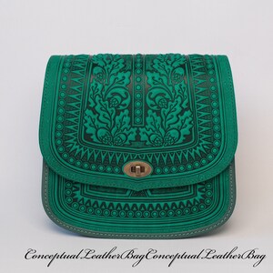 May include: A green leather shoulder bag with an intricate floral design embossed on the front. The bag has a flap closure with a metal clasp.