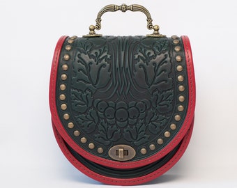 May include: A small, dark green leather handbag with a red trim and brass hardware. The bag has a floral embossed design and is adorned with brass studs.