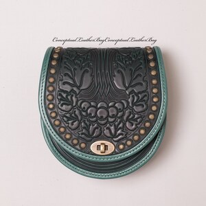May include: A dark green leather bag with a black floral design and gold accents. The bag has a flap closure with a metal clasp.