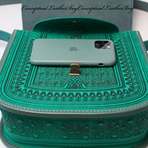 May include: A teal green leather crossbody bag with a flap closure and a decorative embossed pattern. A teal green phone case with a white Apple logo is inside the bag.