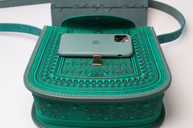 May include: A teal green leather crossbody bag with a flap closure and a decorative embossed pattern. A teal green phone case with a white Apple logo is inside the bag.