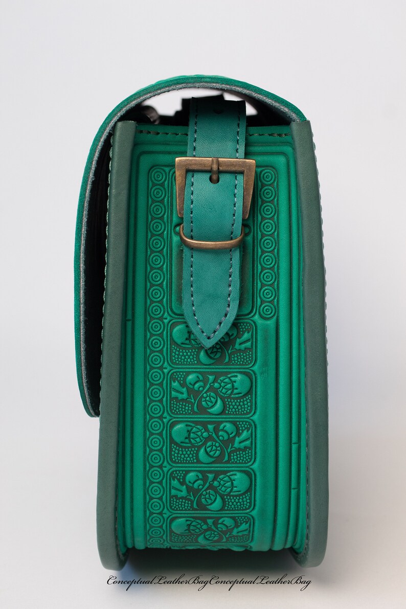 May include: A green leather shoulder bag with a decorative embossed pattern and a brass buckle. The bag has a flap closure and a strap.