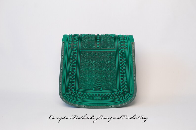 May include: A green leather bag with an intricate geometric pattern embossed on the front. The bag has a flap closure and a small strap.
