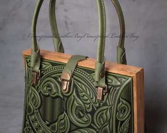 May include: A handcrafted green leather handbag with a wooden frame. The bag features intricate embossed floral designs and a top handle. The bag has a rectangular shape and a clasp closure. The text "Conceptual Leather Bag" is visible.