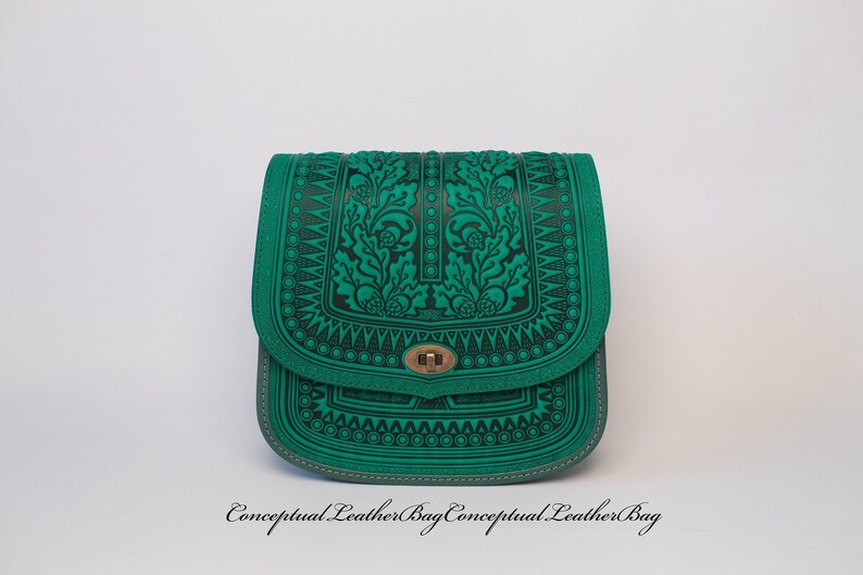 May include: A green leather shoulder bag with an intricate floral design embossed on the front. The bag has a flap closure with a metal clasp.