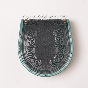 May include: A dark green leather bag with a decorative floral design and a green trim. The bag has a flap closure and a metal buckle.