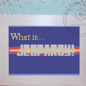 Könnte beinhalten: Ein gerahmtes Kreuzstich-Design mit blauem Hintergrund und dem Text "What is... JEOPARDY!" in Gelb und Weiß.