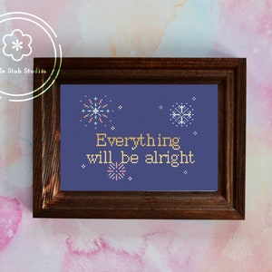 May include: A framed cross-stitch design with a blue background and white and yellow embroidery. The design features fireworks and snowflakes and the text "Everything will be alright".