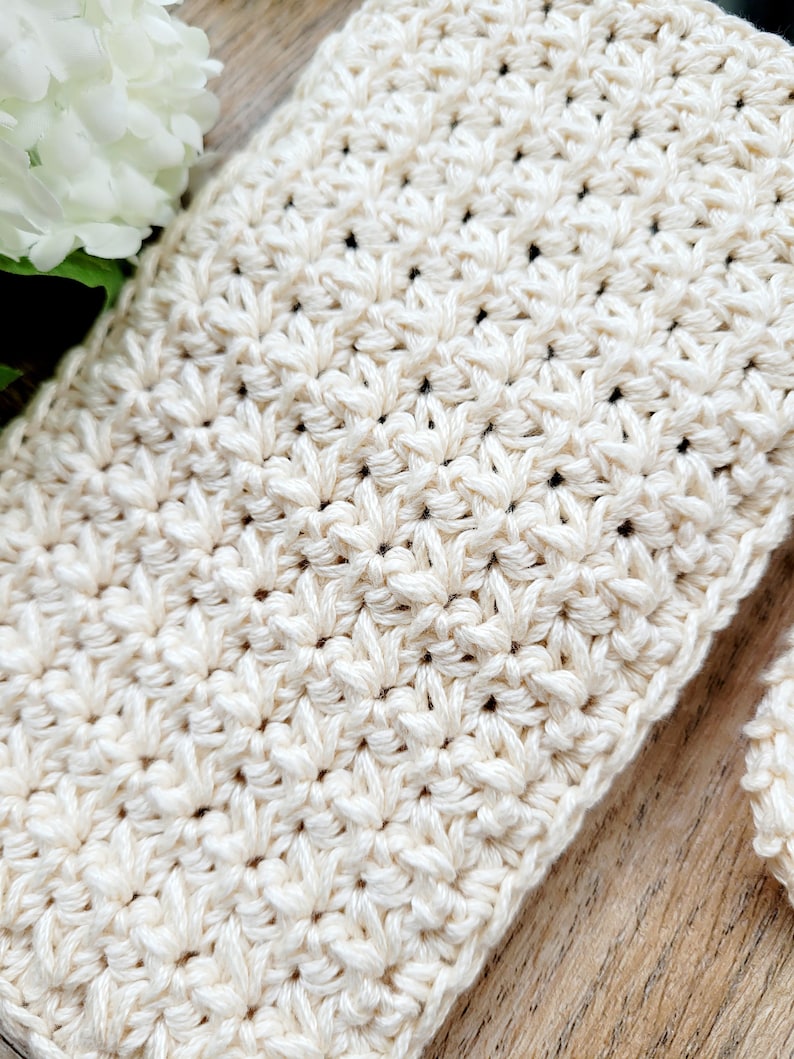 May include: Close-up of a crocheted fabric with a textured pattern in a cream color.
